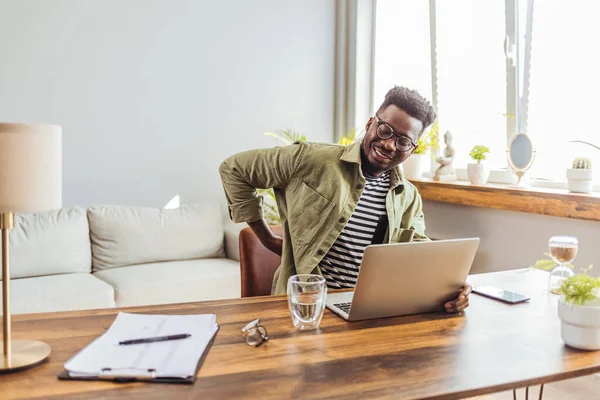 Sırtımda ağrı var. Afrika kökenli Amerikalı adam sırt masajı yaptırıyor belinde ağrı var modern ofiste işyerinde oturmaktan acı çekiyor. Lumbar Ache. Sağlık Sorunu Konsepti.