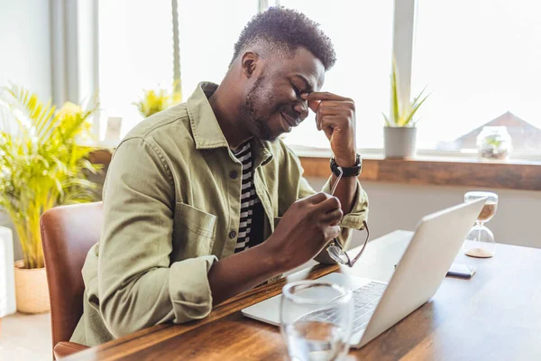 Evde dizüstü bilgisayar kullanarak çalışan yorgun ve endişeli görünen genç bir işadamı. Hüsrana uğramış genç bir adam ofisteki iş yerinde otururken burnuna masaj yapıyor ve gözlerini kapalı tutuyor.