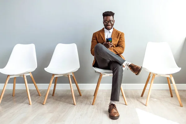 Studioaufnahme Eines Jungen Geschäftsmannes Der Ein Smartphone Benutzt Während Wartet — Stockfoto