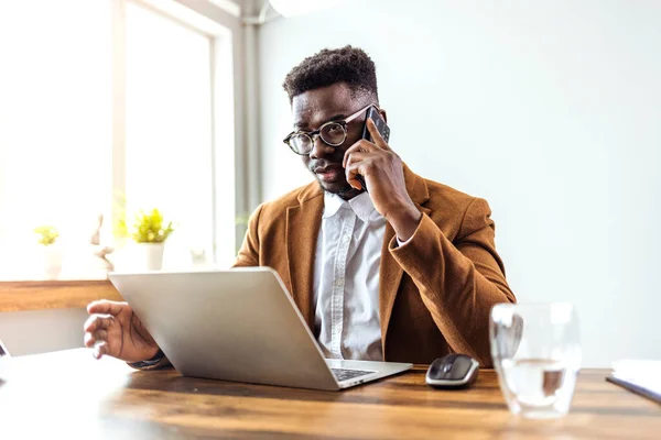 Confident African American Businessman Sitting Desk Laptop Talking Phone — Zdjęcie stockowe