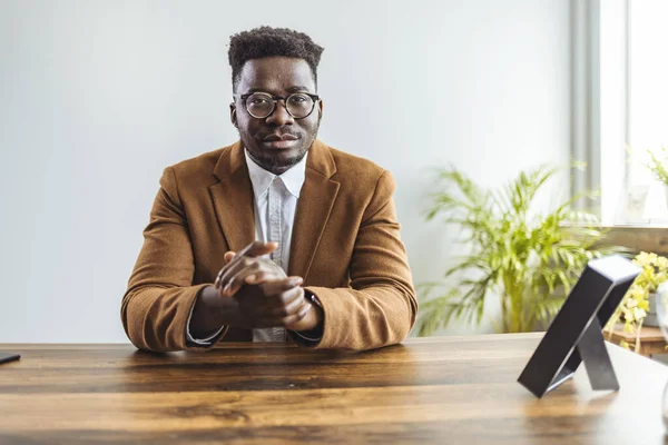 Gözlüklü genç Afro-Amerikan iş adamı kameraya bakıyor ve el kol hareketi yapıyor.