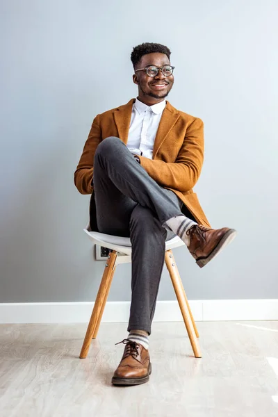 Uśmiechnięty Afrykańsko Amerykański Biznesmen Siedzący Krześle Odwracający Wzrok Studiu — Zdjęcie stockowe