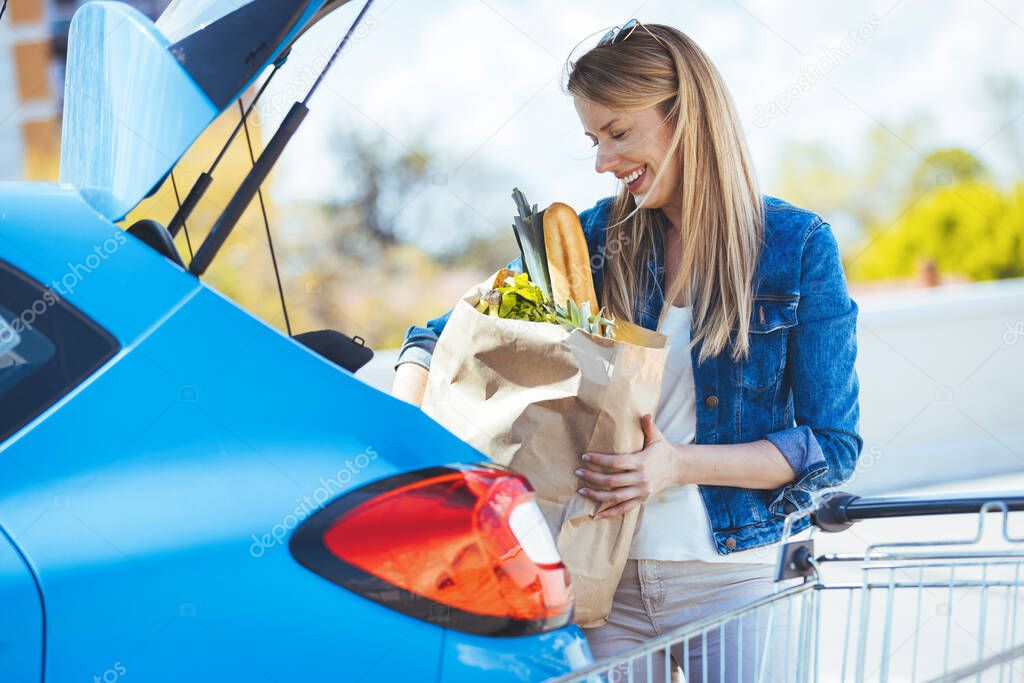 young woman loading groceries in car
