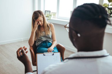 Young frustrated woman solving her mental problems while having therapy session with psychologist. Psychotherapy session, woman talking to his psychologist in the studio. 