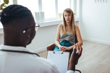 Young frustrated woman solving her mental problems while having therapy session with psychologist. Psychotherapy session, woman talking to his psychologist in the studio. 