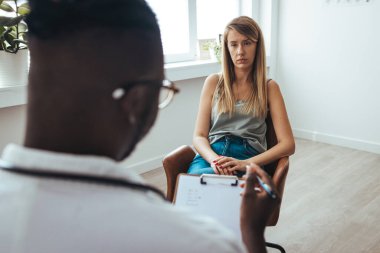 Professional psychotherapies and young woman suffering from ptsd. A young girls meets with a therapist to discuss her struggles, addictions and mental well being. Doctor In Consultation With Depressed Female Patient 
