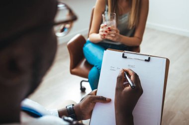 Psychology, depression. Sad, suffering young woman consulting with psychologist, psychiatrist while patient counseling mental with doctor woman taking notes at clinic. Encouraging, therapy.
