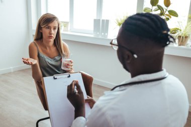Young frustrated woman solving her mental problems while having therapy session with psychologist. Psychotherapy session, woman talking to his psychologist in the studio. 
