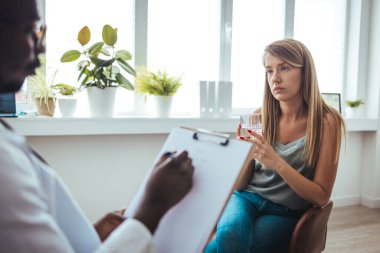 Psychology, depression. Sad, suffering young woman consulting with psychologist, psychiatrist while patient counseling mental with doctor woman taking notes at clinic. Encouraging, therapy.