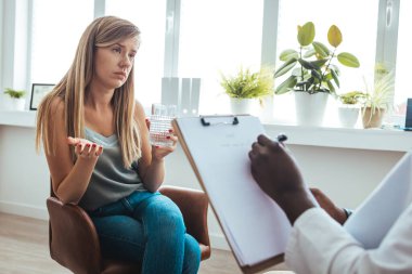 Professional psychotherapies and young woman suffering from ptsd. A young girls meets with a therapist to discuss her struggles, addictions and mental well being. Doctor In Consultation With Depressed Female Patient 