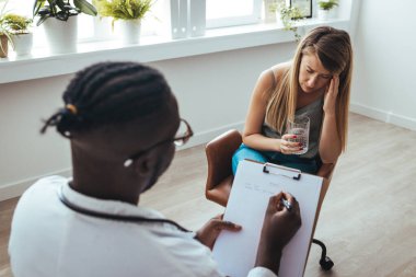 Professional psychotherapies and young woman suffering from ptsd. A young girls meets with a therapist to discuss her struggles, addictions and mental well being. Doctor In Consultation With Depressed Female Patient 