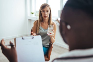 Caring African American psychotherapist consoling young woman during a therapeutic session at his office. A young frustrated girl meets with a therapist to discuss her struggles, addictions and mental well being. 