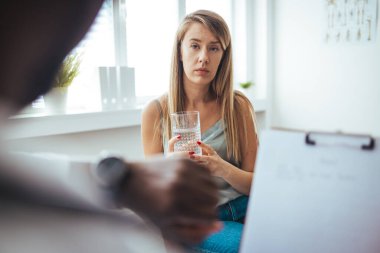 Caring African American psychotherapist consoling young woman during a therapeutic session at his office. A young frustrated girl meets with a therapist to discuss her struggles, addictions and mental well being. 