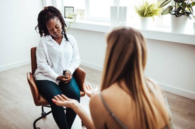 Psychologist listening to her patient and writing down notes, mental health and counseling concept. Shot of an attractive young woman sitting and talking to her psychologist during a consultation