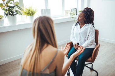 Psychotherapy session, woman talking to his psychologist in the studio. Young woman visiting therapist counselor. Girl feeling depressed, unhappy and hopeless, needs assistance. Serious disease, unwilling pregnancy
