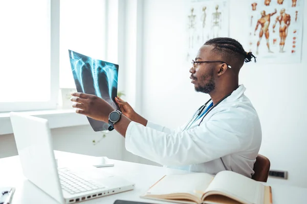Male radiologist analyzing chest X-ray of an patient at medical clinic during coronavirus epidemic. Doctor with radiological chest x-ray film for medical diagnosis on patient\'s health on asthma, lung disease and bone cancer illness