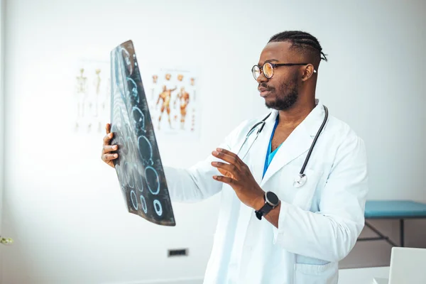 Medical experts studies the EEG condition of the patient. Revealing brain deformations. Qualified smart concentrated radiograph working at the office while holding computed tomography photo