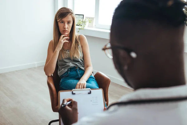 Psychology, depression. Sad, suffering young woman consulting with psychologist, psychiatrist while patient counseling mental with doctor woman taking notes at clinic. Encouraging, therapy.