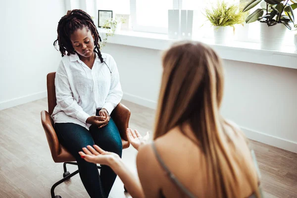 Psychologist listening to her patient and writing down notes, mental health and counseling concept. Shot of an attractive young woman sitting and talking to her psychologist during a consultation