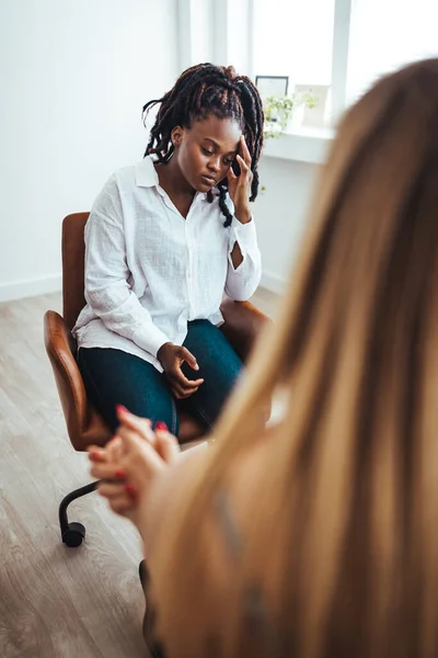 Psychologist listening to her patient and writing down notes, mental health and counseling concept. Shot of an attractive young woman sitting and talking to her psychologist during a consultation
