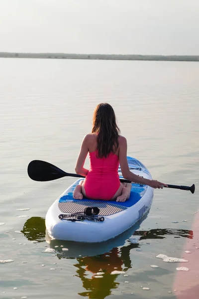 Joven paddle boarding femenino al atardecer. —  Fotos de Stock