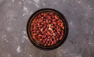 Kabukta kızarmış fıstık, koyu ahşap masada beyaz cam tabakta soyulmuş yer fıstığı..