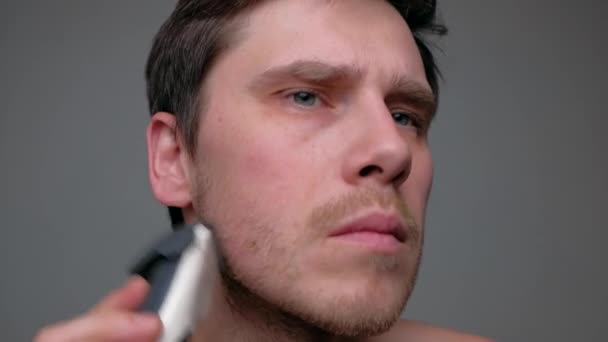 Человек бреется с электрической бритвой. — стоковое видео