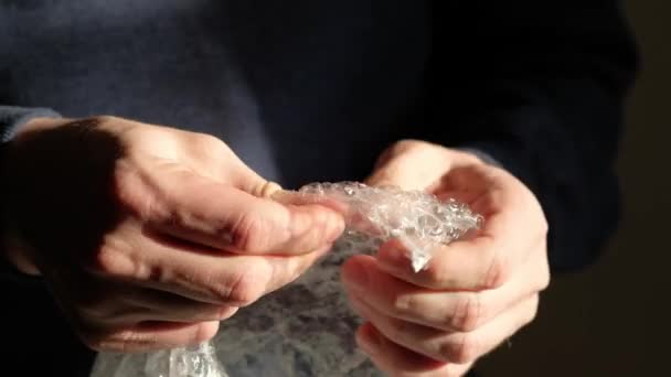 Mains humaines éclatant les bulles dans un emballage à bulles. Mise au point sélective, gros plan. — Video
