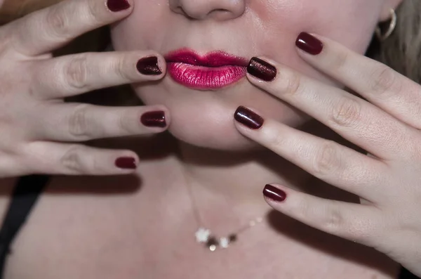 Dudaklarında kırmızı ruj lekesi olan kadın eli, yakın çekim görüntüsü. Moda konsepti Manikürlü tırnaklar.