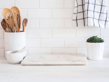 Beyaz mutfak arka planında mutfak gereçleri ve beyaz tezgahta duran yeşil ev bitkisi, metin için kopyalama alanı, ön görünüm