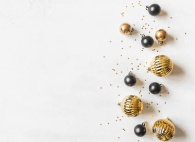 Tebrik kartı - mutlu yıllar ve mutlu Noeller, altın yıldızlar parıldıyor ve beyaz desenli arka planda siyah ve altın noel baloları. Minimum tatil konsepti. Üst Manzara. Düz yatıyordu