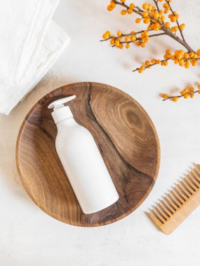 Pompalı beyaz plastik şişe, şampuan ve ahşap tepside saç kremi ve beyaz arka planda ahşap tarak için kullanılır. Üst görünüm