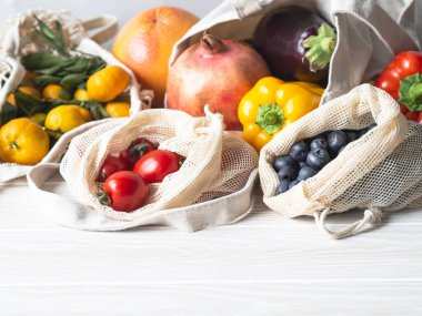 Mutfaktaki masada taze sebzeler ve eko pamuklu poşetlerde meyveler. Sıfır atık alışveriş kavramı. Ön manzara. Boşluğu kopyala.