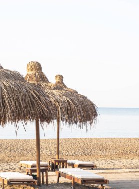 Boş sahil sahillerinde saman şemsiyeler. Plaj tatili