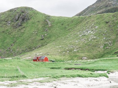 Dağlarla çevrili geleneksel kırmızı ahşap Norveç çiftlik evi. Ayrı bir evde. Asgari manzara