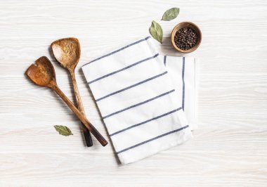 Pamuk peçete, çeşitli baharatlar ve ahşap aletlerle en az beyaz mutfak arka planı. Mutfak gereçleri beyaz sehpada. Boşluğu kopyala, üst görünüm