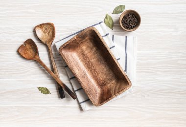 Beyaz mutfak arka planı kahverengi tabak, çeşitli baharatlar, aletler ve pamuk peçeteyle. Eko mutfak aletleri dokunun beyaz masasında. Boşluğu kopyala, üst görünüm