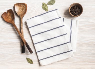 Pamuk peçete, çeşitli baharatlar ve ahşap aletlerle en az beyaz mutfak arka planı. Mutfak gereçleri beyaz sehpada. Boşluğu kopyala, üst görünüm
