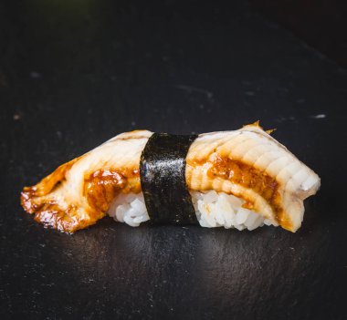 Suşi böreği (Maguro) karides, füme yılan balığı, avokado, siyah arka planda Philadelphia peyniri. Suşi menüsü. Japon yemeği..