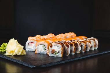 Sushi roll (Maguro) with shrimp, smoked eel, avocado, philadelphia cheese on black background. Sushi menu. Japanese food.