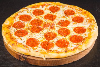 Lezzetli biberli pizza ve siyah beton arka planda domates fesleğeni. Acı biberli pizzanın en iyi manzarası. Pankart