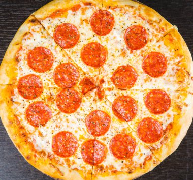 Lezzetli biberli pizza ve siyah beton arka planda domates fesleğeni. Acı biberli pizzanın en iyi manzarası. Pankart