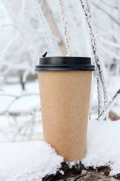 Paket kahve bardağı. Mesajlaşmak için bir fincan kahve. Kışın kahve içmek için arka planda.