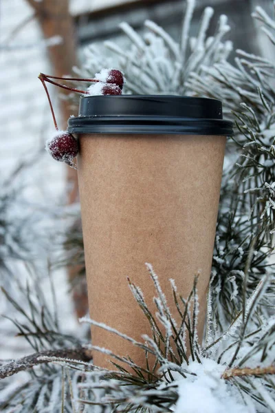 Paket kahve bardağı. Mesajlaşmak için bir fincan kahve. Kışın kahve içmek için arka planda.