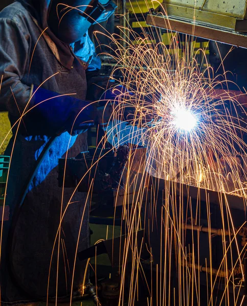 Endüstriyel üniforma giyen ve çelik maskeli işçiler