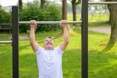Sağlıklı, aktif bir yaşam tarzı konsepti olan bir parkta bahar egzersizi yaparken kollarını kaldırmaya çalışan kıdemli bir adam.