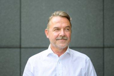 Tişörtlü, kendinden emin orta yaşlı işadamının yan görünüm portresi.