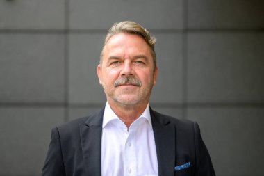 Kendine güvenen orta yaşlı bir işadamının resmi.