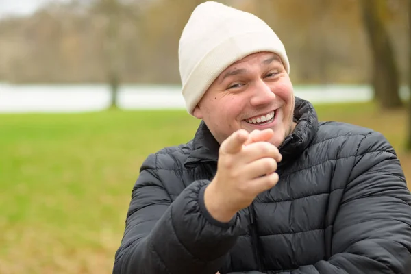 Sıcak Kışlık Ceketli Bereli Genç Adam Parktaki Kamerayı Işaret Ederek — Stok fotoğraf