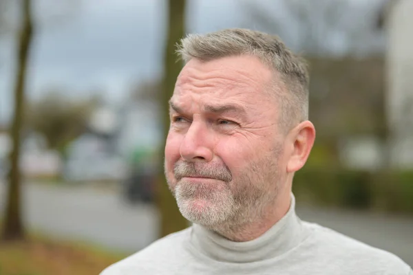 Man looking aside with an anxious expression squinting his eyes with a troubled frown in close up